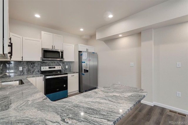 kitchen with visible vents, decorative backsplash, light stone countertops, stainless steel appliances, and a sink