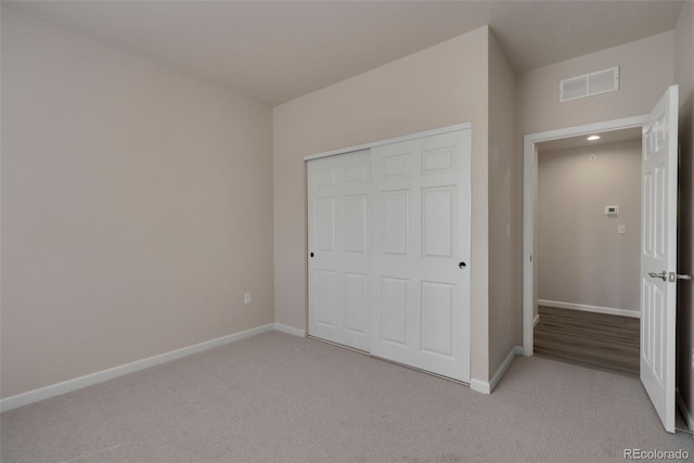 unfurnished bedroom featuring a closet, visible vents, light carpet, and baseboards