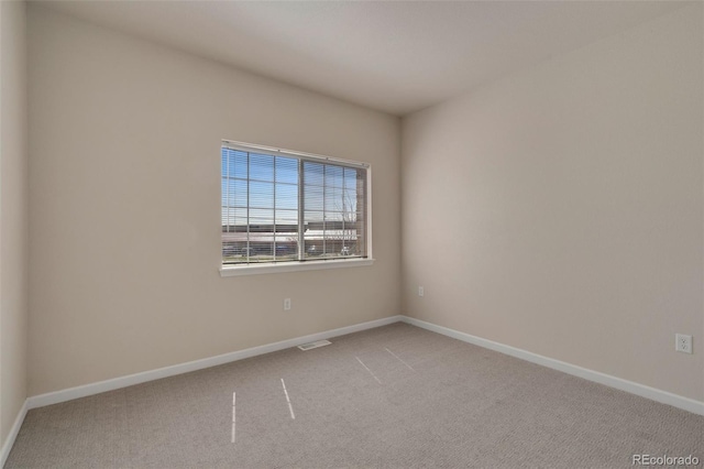 spare room with carpet flooring, visible vents, and baseboards