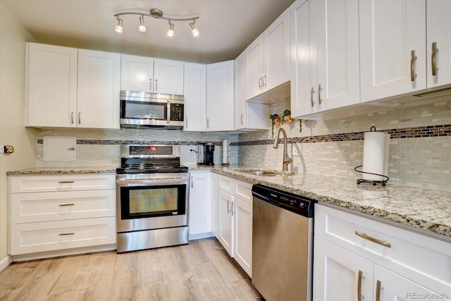 kitchen featuring light wood-type flooring, white cabinetry, appliances with stainless steel finishes, and a sink