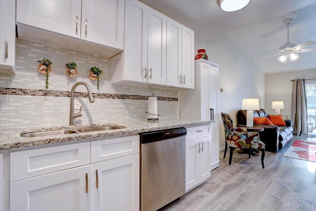 kitchen featuring tasteful backsplash, light wood-style flooring, stainless steel dishwasher, white cabinetry, and a sink