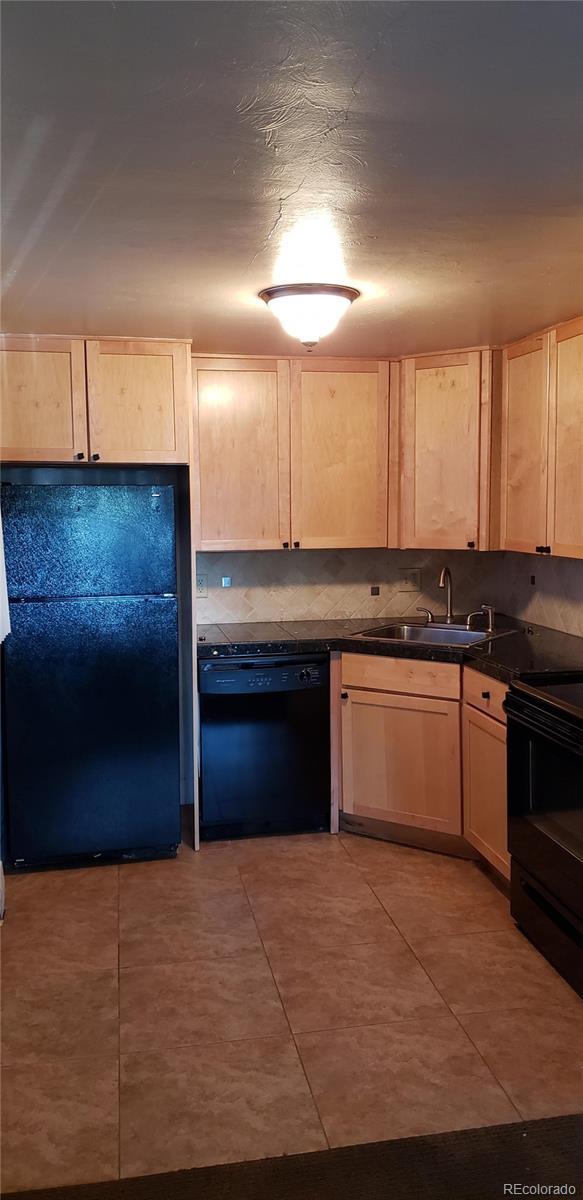 kitchen featuring backsplash, dark countertops, a sink, black appliances, and light brown cabinets