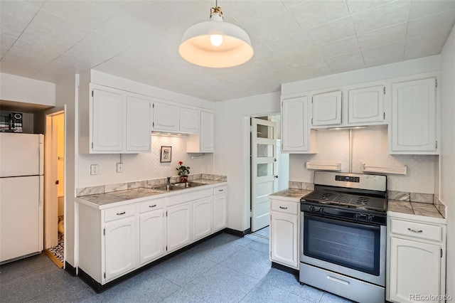 1654 S Pearl St, Denver, CO 80210 - kitchen featuring stainless steel gas range, freestanding refrigerator, white cabinetry, decorative backsplash, and tile counters