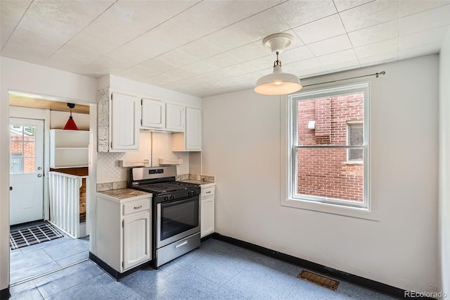 1654 S Pearl St, Denver, CO 80210 - kitchen featuring stainless steel range with gas cooktop, white cabinets, light countertops, decorative backsplash, and pendant lighting