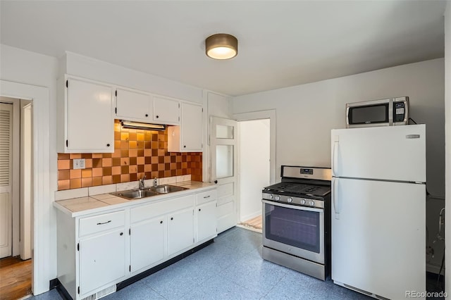 1654 S Pearl St, Denver, CO 80210 - kitchen with appliances with stainless steel finishes, white cabinetry, tasteful backsplash, tile patterned floors, and tile countertops