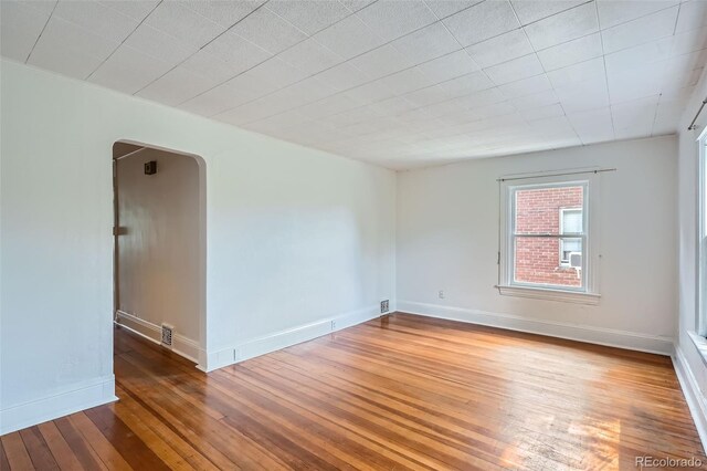 1654 S Pearl St, Denver, CO 80210 - empty room featuring arched walkways and hardwood / wood-style flooring