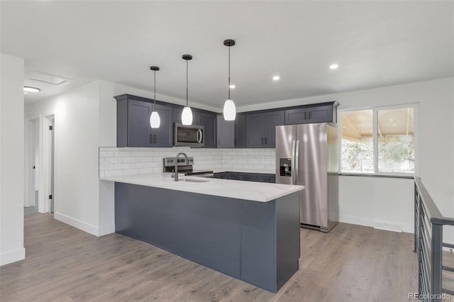 9008 Dover St, Broomfield, CO 80021 - kitchen with stainless steel appliances, a peninsula, light countertops, backsplash, and wood finished floors