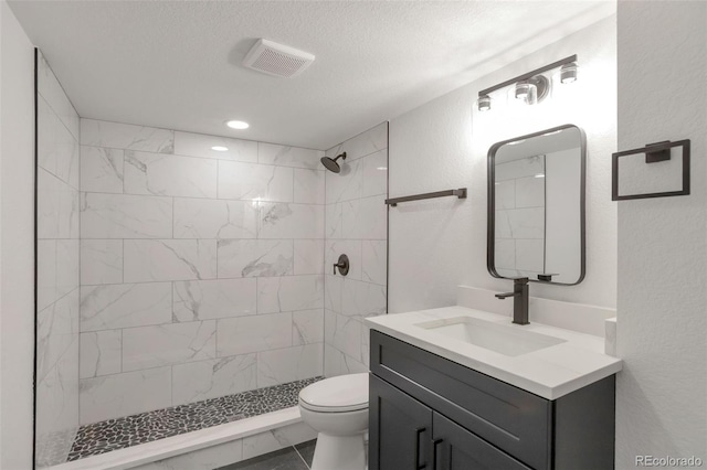 9008 Dover St, Broomfield, CO 80021 - bathroom with tiled shower, vanity, marble finish floors, a textured ceiling, and a textured wall