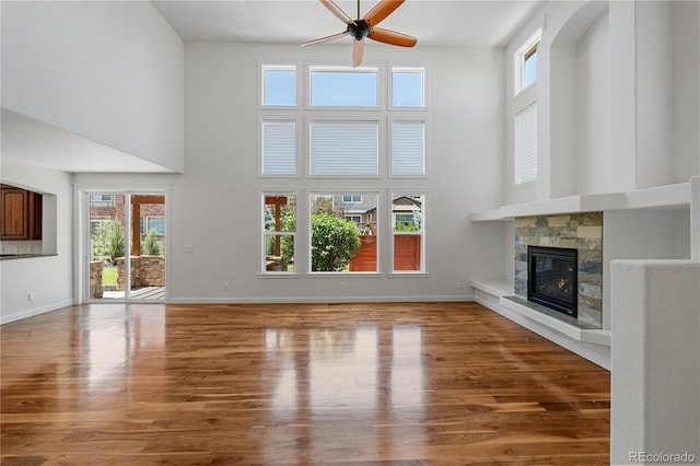 14325 N Santa Fe St, Broomfield, CO 80023 - unfurnished living room featuring a towering ceiling, ceiling fan, a fireplace, and wood finished floors