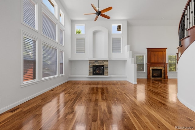 14325 N Santa Fe St, Broomfield, CO 80023 - unfurnished living room with a fireplace, wood finished floors, ceiling fan, plenty of natural light, and a towering ceiling