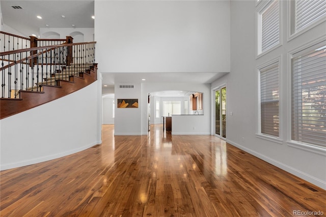 14325 N Santa Fe St, Broomfield, CO 80023 - unfurnished living room featuring arched walkways, a high ceiling, wood finished floors, and stairs