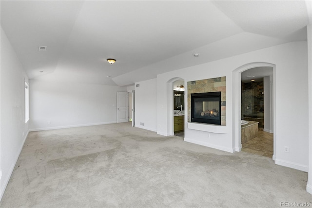 14325 N Santa Fe St, Broomfield, CO 80023 - unfurnished living room featuring vaulted ceiling, light colored carpet, arched walkways, and a multi sided fireplace