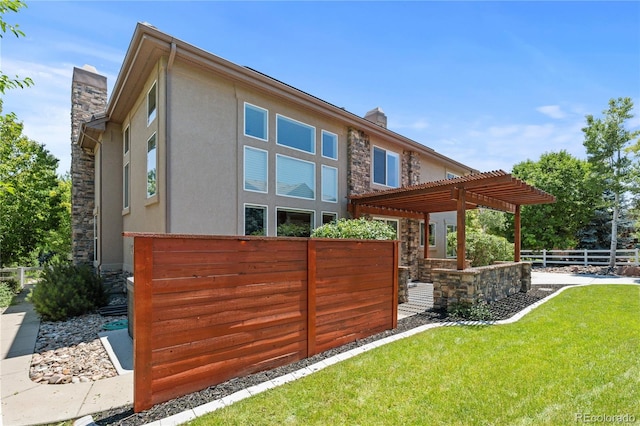 14325 N Santa Fe St, Broomfield, CO 80023 - rear view of property featuring stone siding, a chimney, stucco siding, a pergola, and a fenced backyard