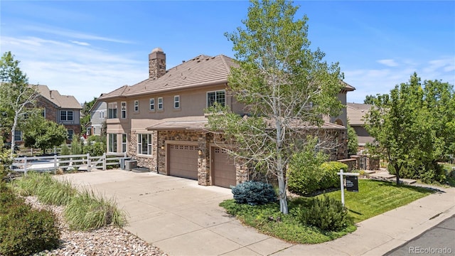 14325 N Santa Fe St, Broomfield, CO 80023 - view of front facade with stucco siding, an attached garage, stone siding, driveway, and a chimney