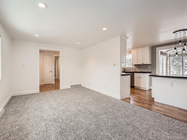 unfurnished living room with sink and carpet flooring