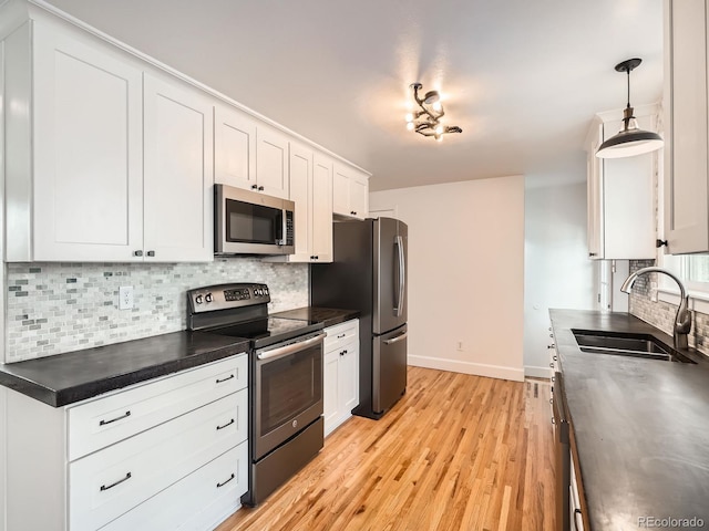 kitchen with sink, backsplash, appliances with stainless steel finishes, and white cabinetry