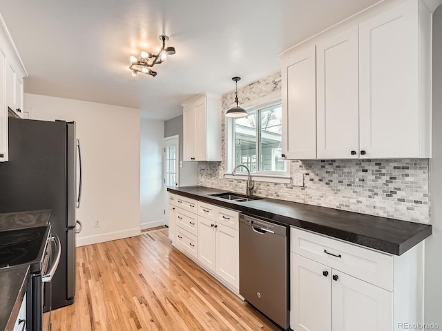 kitchen with sink, appliances with stainless steel finishes, white cabinets, and pendant lighting