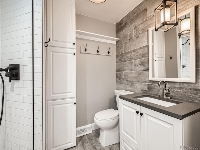 bathroom featuring wood-type flooring, vanity, wood walls, and toilet