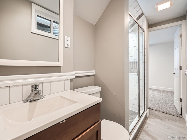 bathroom featuring lofted ceiling, vanity, walk in shower, toilet, and hardwood / wood-style flooring