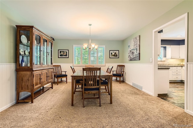 dining room with wainscoting, carpet, and a chandelier