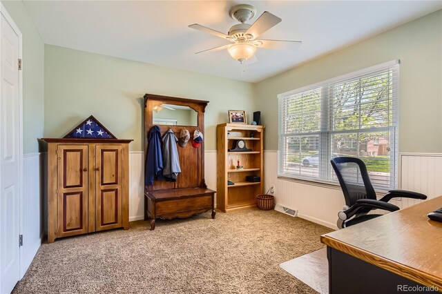 home office featuring wainscoting, light carpet, and a ceiling fan