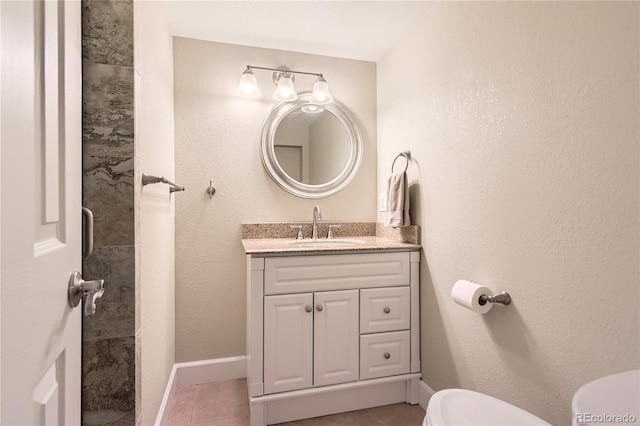 bathroom featuring toilet, vanity, tile patterned flooring, and baseboards