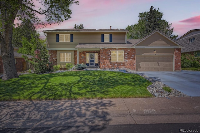 traditional-style home with brick siding, a garage, concrete driveway, and a yard