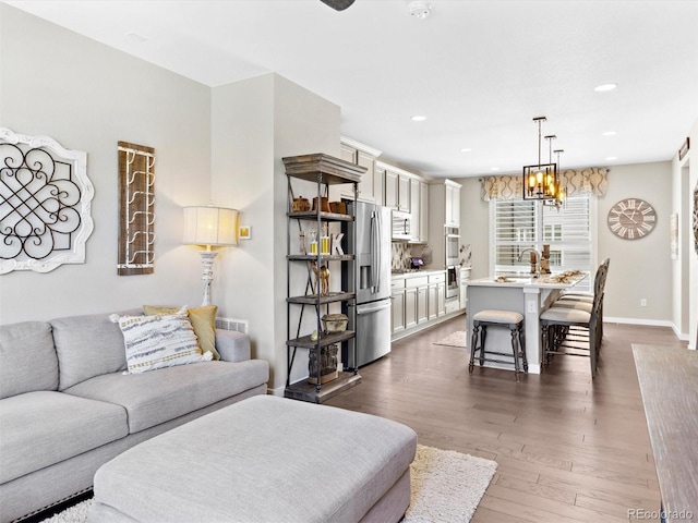 living area with recessed lighting, dark wood-style flooring, a chandelier, and baseboards