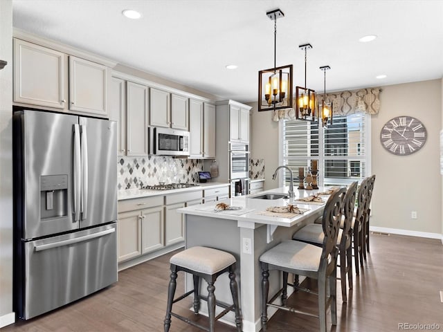kitchen featuring appliances with stainless steel finishes, a sink, tasteful backsplash, dark wood-style floors, and a chandelier