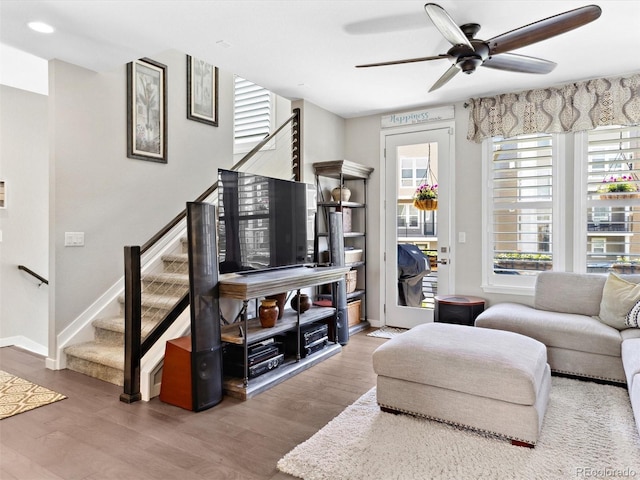 living area with stairs, a ceiling fan, wood finished floors, and baseboards