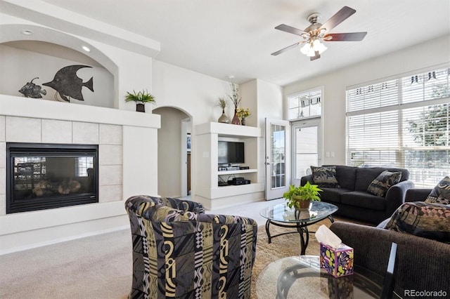 3742 E 127th Ln, Thornton, CO 80241 - living room with carpet flooring, a tiled fireplace, a ceiling fan, and arched walkways