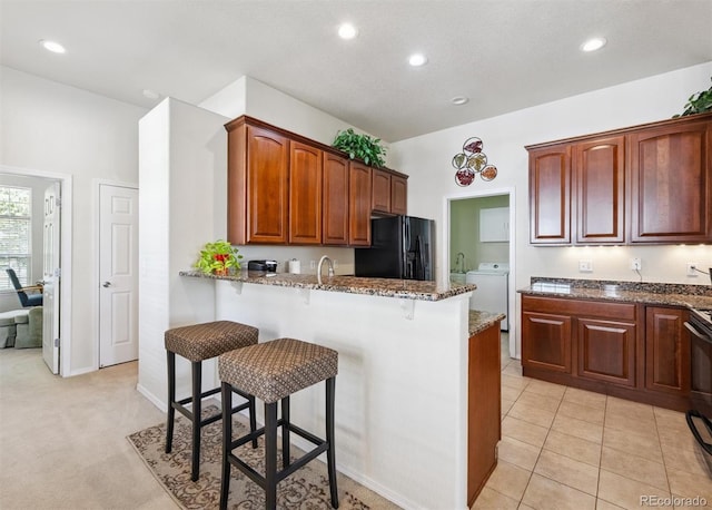 3742 E 127th Ln, Thornton, CO 80241 - kitchen with black refrigerator with ice dispenser, dark stone counters, a kitchen breakfast bar, a peninsula, and recessed lighting