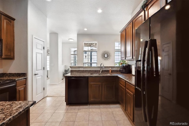 3742 E 127th Ln, Thornton, CO 80241 - kitchen featuring black appliances, a peninsula, dark stone counters, light tile patterned flooring, and recessed lighting