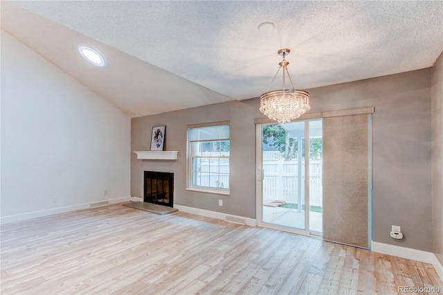 2790 S Wheeling Way, Aurora, CO 80014 - unfurnished living room featuring wood finished floors, a chandelier, a fireplace with raised hearth, lofted ceiling, and a textured ceiling