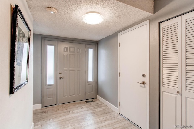 foyer entrance with light wood-type flooring and a textured ceiling