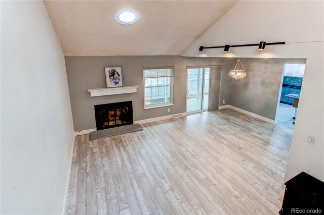 2790 S Wheeling Way, Aurora, CO 80014 - unfurnished living room with a fireplace with raised hearth, lofted ceiling, wood finished floors, a textured ceiling, and a chandelier