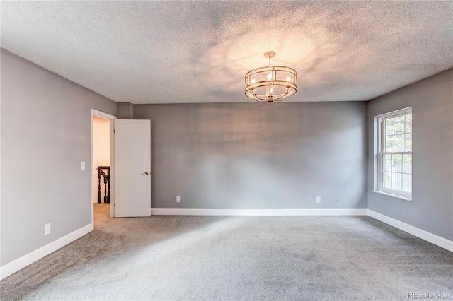 spare room with a chandelier, carpet, and a textured ceiling