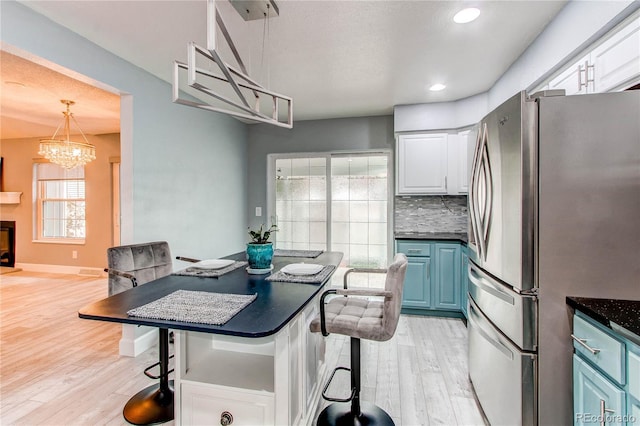 2790 S Wheeling Way, Aurora, CO 80014 - kitchen with freestanding refrigerator, blue cabinetry, dark countertops, a kitchen breakfast bar, and recessed lighting