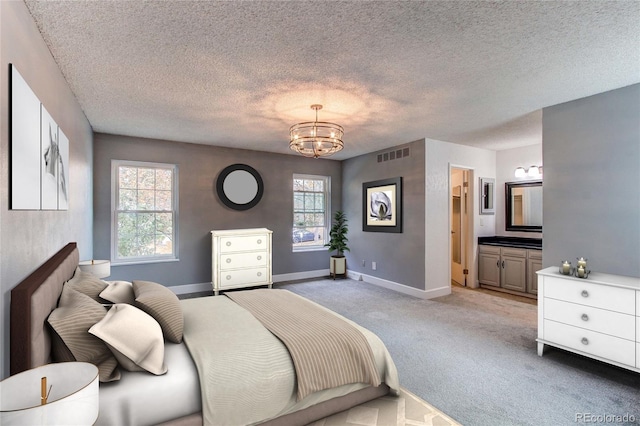 bedroom featuring a textured ceiling, ensuite bath, light carpet, and multiple windows