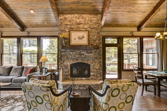 living room with hardwood / wood-style floors, a stone fireplace, wooden ceiling, and plenty of natural light