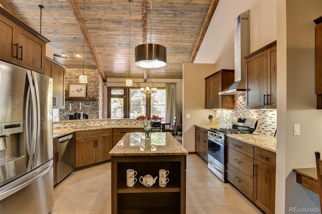 kitchen featuring appliances with stainless steel finishes, tasteful backsplash, light stone counters, wall chimney range hood, and a kitchen island