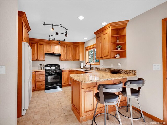 385 Pine Dr, Fairplay, CO 80440 - kitchen with under cabinet range hood, a sink, gas stove, a peninsula, and white fridge with ice dispenser
