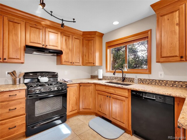 385 Pine Dr, Fairplay, CO 80440 - kitchen with light stone counters, under cabinet range hood, a sink, light tile patterned floors, and black appliances