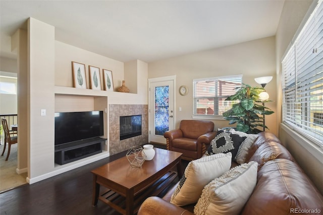 living room with a tile fireplace and dark hardwood / wood-style floors