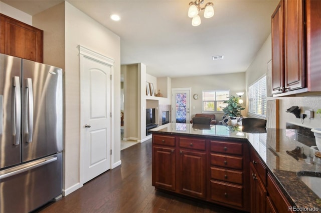 kitchen featuring dark stone countertops, stainless steel fridge, and dark hardwood / wood-style flooring