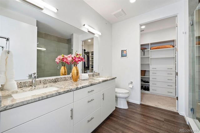 bathroom with a shower with door, vanity, hardwood / wood-style floors, and toilet