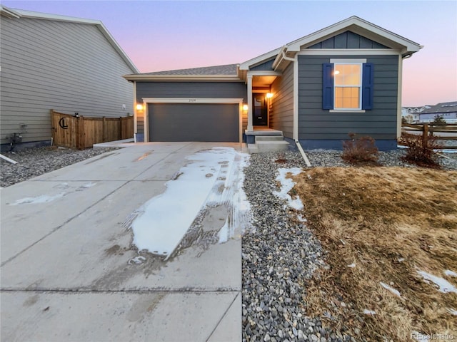 view of front of home with an attached garage, fence, board and batten siding, and concrete driveway