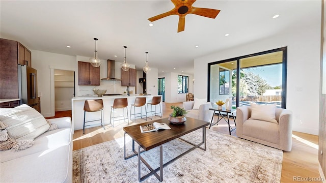 living room featuring ceiling fan, light wood-type flooring, and sink