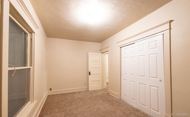 unfurnished bedroom with carpet, a textured ceiling, and a closet