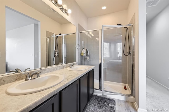 bathroom with hardwood / wood-style floors, walk in shower, and vanity